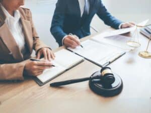 Due avvocati lavorano insieme alla scrivania, con documenti legali e un martelletto, simbolo di consulenza e pratiche di recupero crediti.