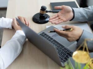 rappresentazione di una consulenza recupero crediti con due persone che discutono con documenti legali e computer